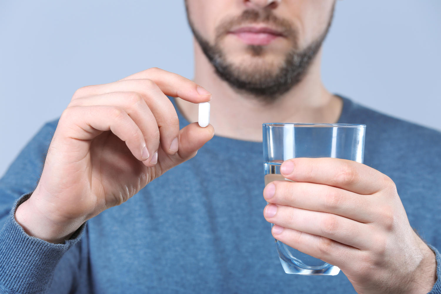 Uomo con in mano una compressa e un bicchiere d'acqua