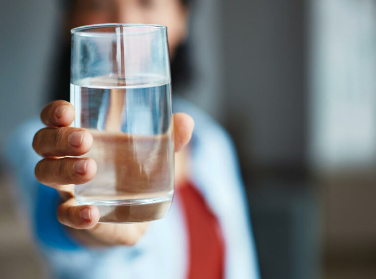 Bicchiere d'acqua tenuto da da una donna