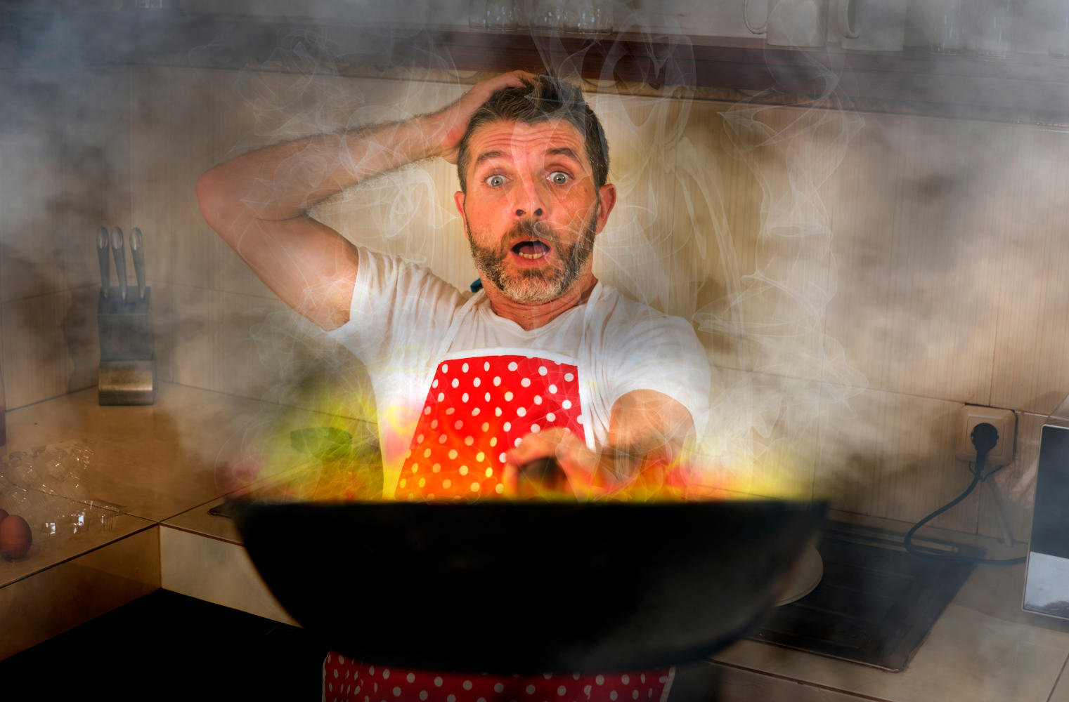 Padella in fiamme in mano a un uomo che cucina