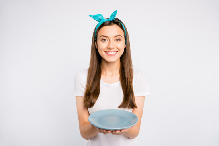 Ragazza sorridente con un piatto vuoto