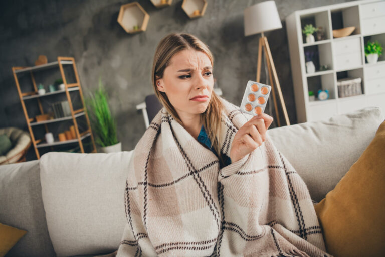 Ragazza influenzata con in mano una scatola di farmaci