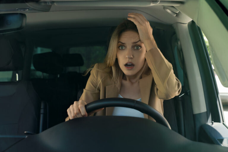 Donna al volante con sguardo sorpreso