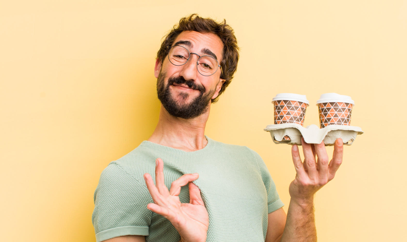 Uomo con due tazze di caffè in mano e sguardo ammiccante