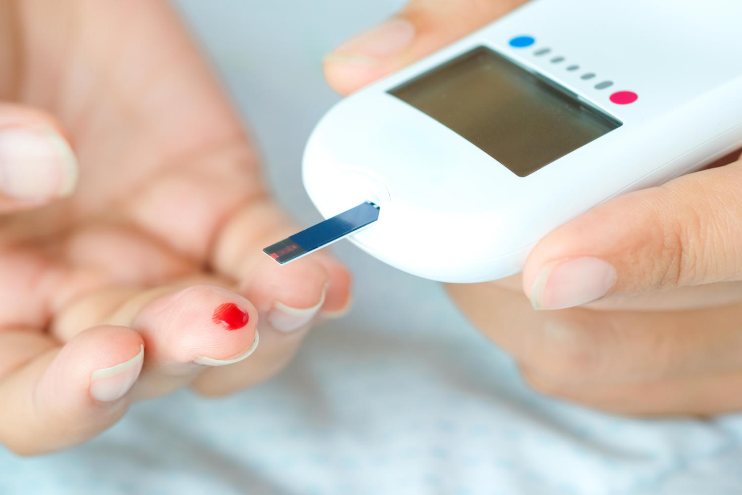 Glucometro e dito con una goccia di sangue