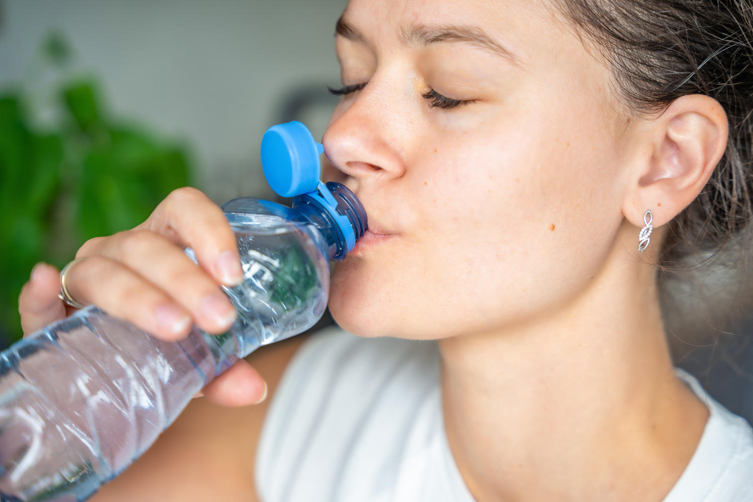 Ragazza che beve da una bottiglia di plastica