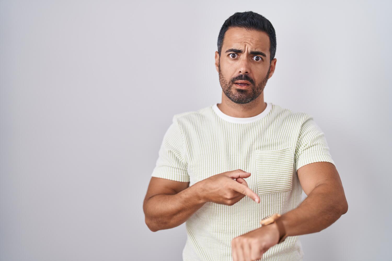 Uomo che indica con sguardo sorpreso il suo orologio