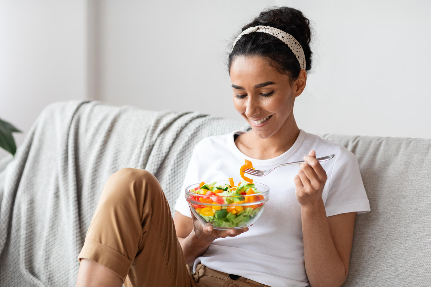 Ragazza mangia un'insalata sul divano