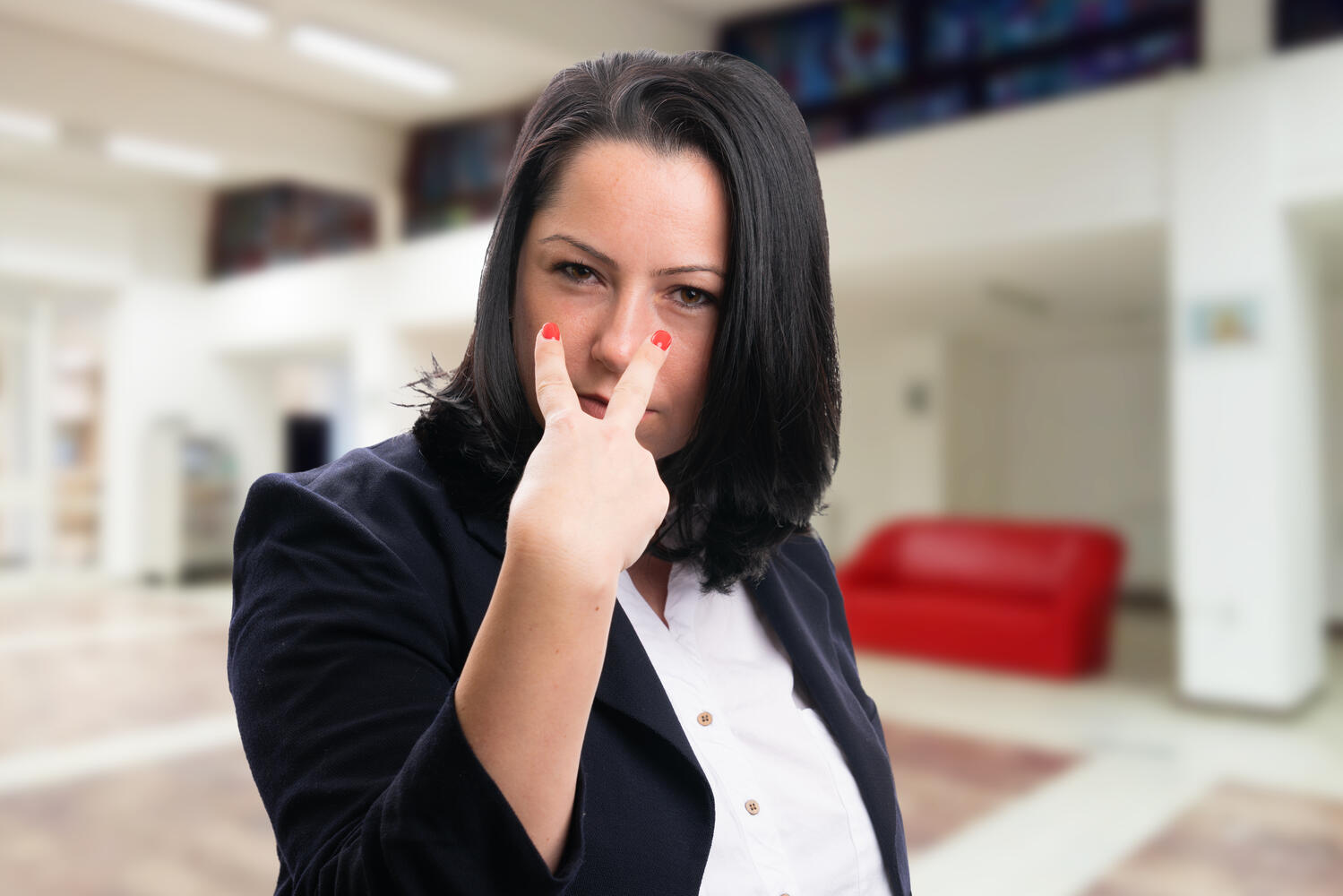 Donna in elegante abito da ufficio fa il gesto "guardami negli occhi"