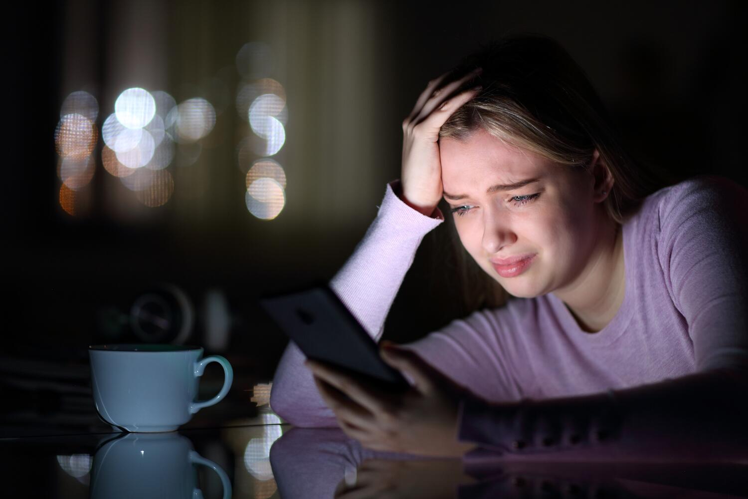 Ragazza triste guarda il cellulare nella notte