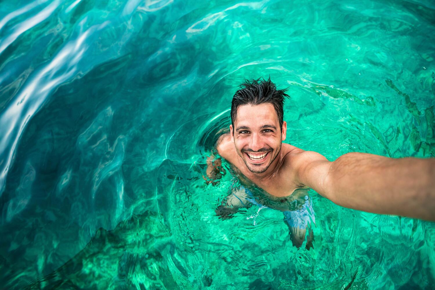 Uomo felice che si scatta un selfie mentre nuota nell'oceano