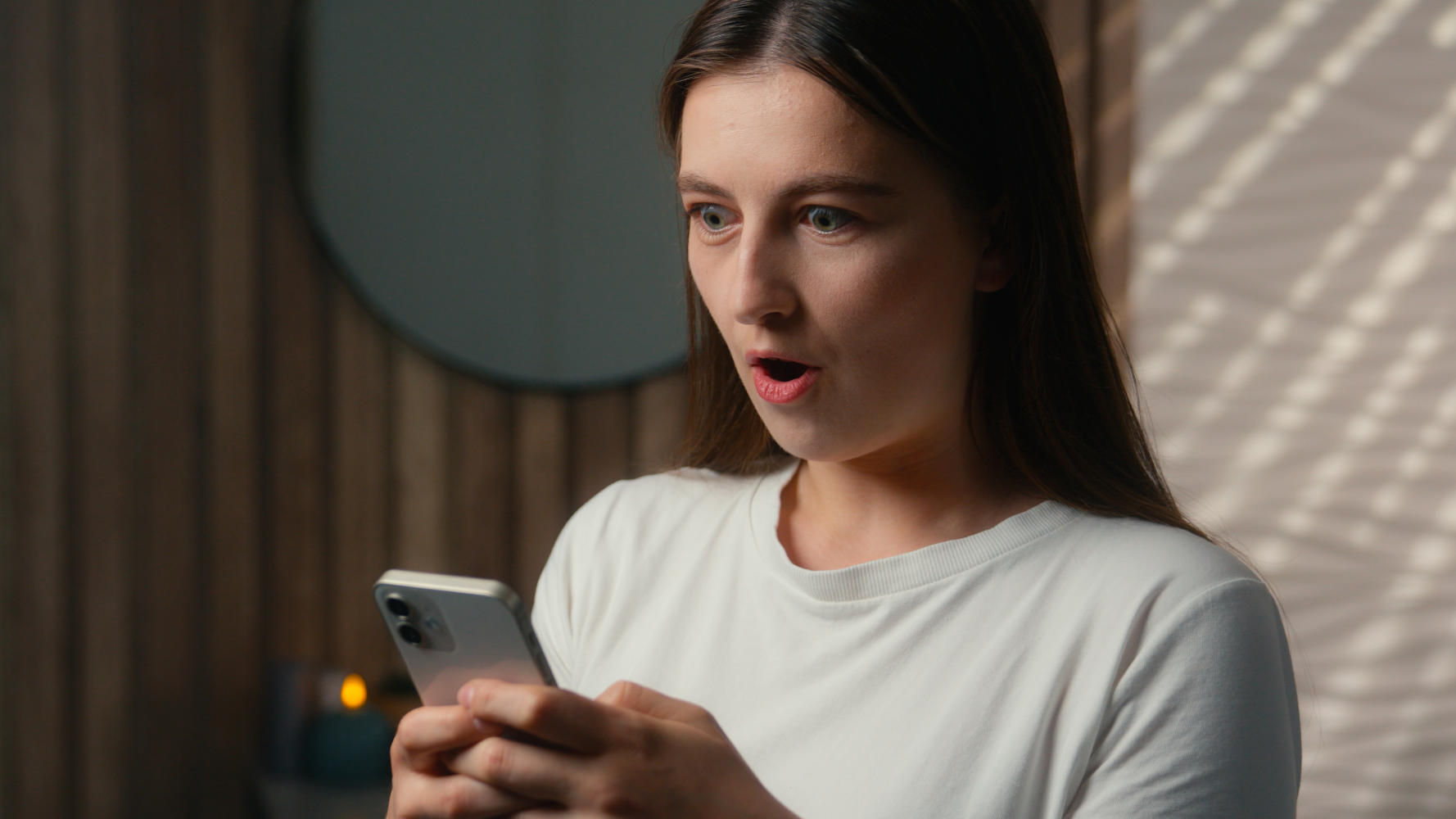 Ragazza che guarda lo smartphone con espressione sorpresa