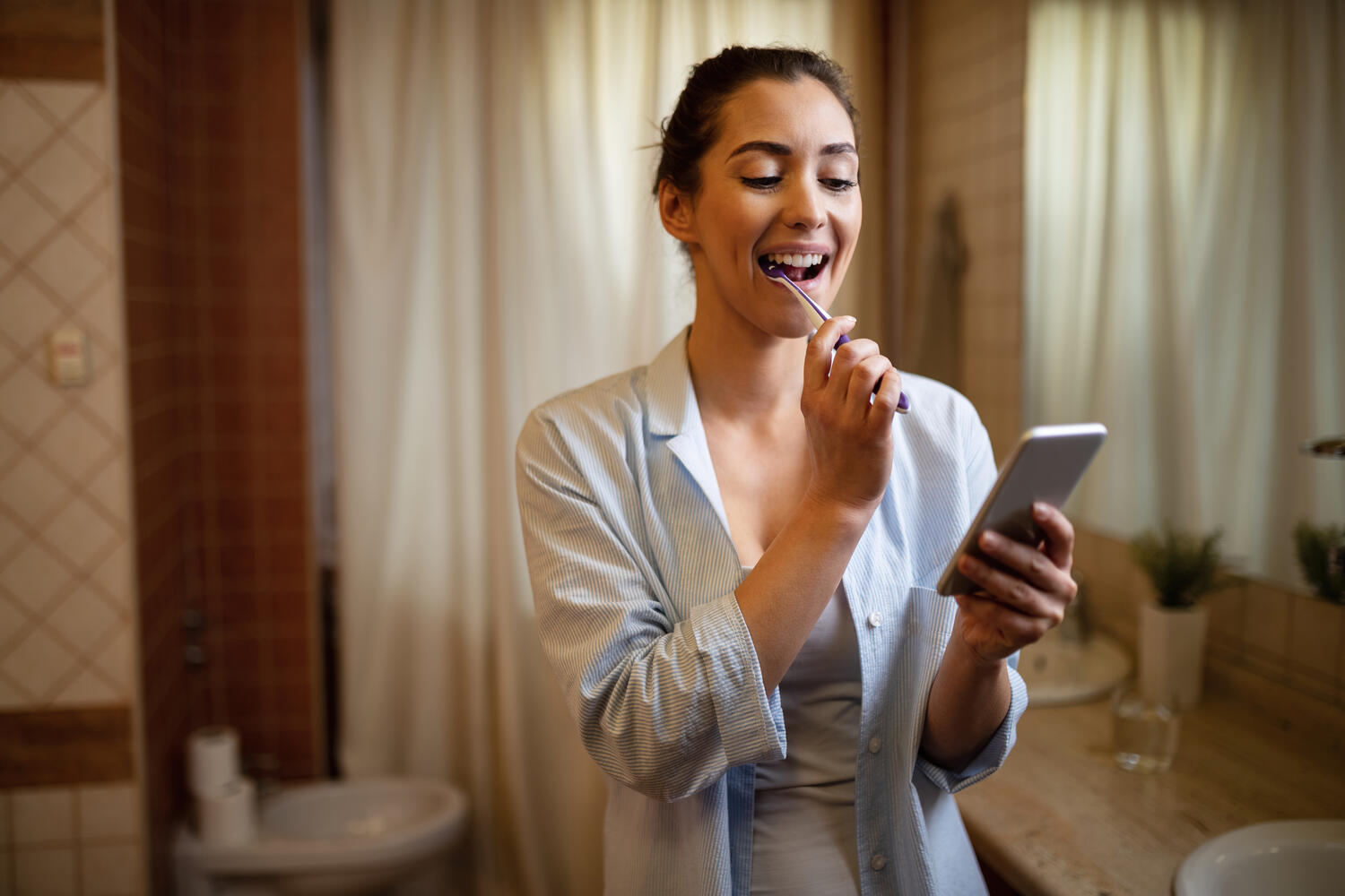 Ragazza che si lava i denti con il cellulare in mano