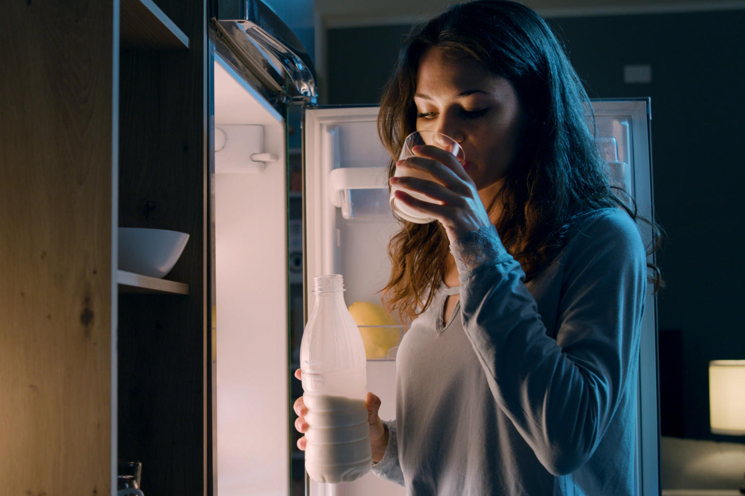 Donna che beve del latte di notte